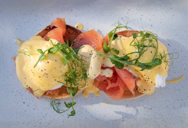 İngiliz keki, meşe füme somonu, haşlanmış tavuk yumurtası ve mavi seramik tepside servis edilen su teresi ile yapılmış yumurta Royale yumurtalarının üst görüntüsü. Duvar kağıdı olarak kullan, Poster ve Kopyala alanı, Seçici odak.