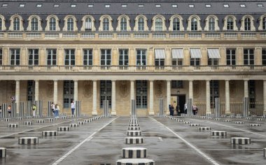 Palais Royal 'in Onur avlusuna yerleştirilen Burens Sütunlarının (iki tepsi) keyfini çıkaran turistler, 260 siyah ve beyaz çizgili sütundan oluşan Çağdaş Sanat, tüm sütunlar bodrumda kök salmış ve dışarıya çıkmıştır. Metin için boşluk.