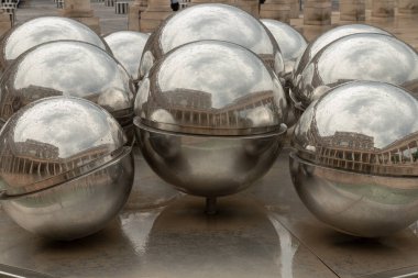 Fontaines de Pol Bury 'deki (La Fontaine des Spheres) 10 paslanmaz çelik kürenin görüntüsü yavaşça eksenlerinde döner, su akışının üstlerine doğru akması Palais-Royal Şeref Sarayı' nda yoldan geçenleri yansıtır..