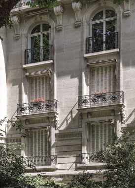 Fransa, Paris - 3 Mayıs 2025 - Geleneksel Fransız panjurları ve pencereleri olan ve Paris 'in merkezinde bulunan demirden siyah korkuluklar döşeyen geleneksel Fransız konut binasının çarpıcı manzarası. Paris binasının ön cephesi.