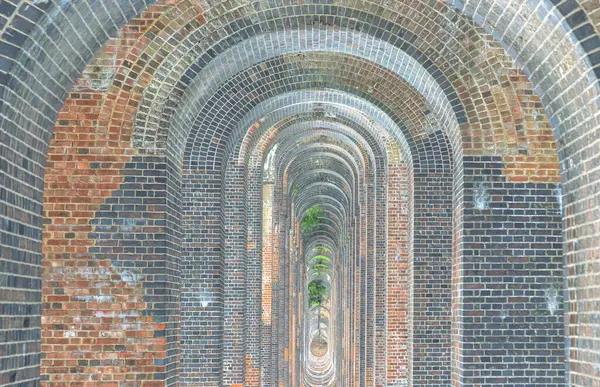 Yarı dairesel kemerler, düz kireçtaşıyla kaplı geleneksel kırmızı tuğla iskelesini destekliyor ve İngiltere 'deki en zarif viyadük olarak tanımlanıyor. Ouse Viyadük ya da Balcombe Viaduct, Brighton Ana Hattı 'nı Ouse Nehri' nden geçirir.