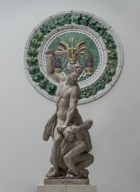 Samson, Giambologna 'nın bir Filistinliyi katletmesi, Seramik heykel ile çatışmaya girmiş iki çıplak adamla mermer heykel, Victoria ve Albert Müzesi' nin arka planında sergilenen beyaz duvarda Kral Rene 'nin Stemma' sı (arma).