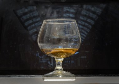 Viski bardağı ya da brendi bardağı dizüstü bilgisayarın üzerinde duruyor ve arka planda laptop ekranı var. Metin, Seçici odak için Duvar Kağıdı, Poster ve Boşluk olarak kullan.