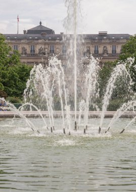 Fransa, Paris - Mayıs 03, 2025 - Arka planda Palais Royal binası ve gökyüzü olan Jardin du Palais Royal çeşmesinin manzarası. 