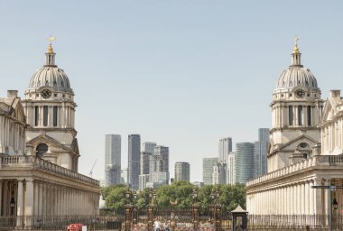 Greenwich 'teki Eski Kraliyet Donanma Koleji' nin ikiz kubbeli ikiz binalarıyla yükselen Kanarya Rıhtımı 'nın çarpıcı manzarası çarpıcı bir ön plan unsuru. Londra 'da eski ve yeni, klasik ve modern arasındaki zıtlık.