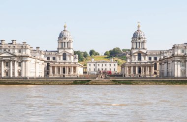 Eski Kraliyet Donanma Koleji 'nin ikiz kubbeli binaları arasında Kraliçe' nin Evi 'nin ötesinde Greenwich Park' taki tepenin ardında yer alan Kraliyet Gözlemevi 'dir. ve Thames nehri ön planda.
