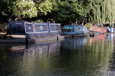 Londra, İngiltere - 21 Haziran 2025 - Batı Londra 'da Küçük Venedik' in pitoresk bir bölgesi, Büyük Birlik Kanalı ve Vekil Kanalı 'nın kavşak noktası, sakin kanalları ve dar kayıklar ve yüzen evlerle dolu su yolları. Duvar kağıdın olarak kullan.