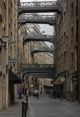 Shad Thames 'in ikonik caddesi boyunca manzaraya bakın ve tarihi kaldırımlı cadde, tuğla yapı ve Butlers Rıhtımı' ndaki depo dairelerini birbirine bağlayan köprüleri de içeren Viktorya dönemi depo mimarisine sahip..
