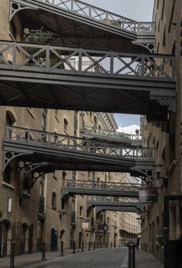 Shad Thames 'in ikonik caddesi boyunca manzaraya bakın ve tarihi kaldırımlı cadde, tuğla yapı ve Butlers Rıhtımı' ndaki depo dairelerini birbirine bağlayan köprüleri de içeren Viktorya dönemi depo mimarisine sahip..