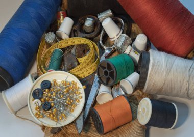 Yeşil minyatür makaralara dikiş iğneleri, iplik makasları, çeşitli renkte iplikler, Yüksük ve Ölçü bantları, küçük yuvarlak tepside iğne ve düğmeler. Nesneler dikişleniyor ya da dikiş nesneleri (kavramları dikiliyor), boşluk kopyala.