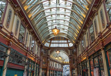 Londra, İngiltere - 27 Haziran 2025 - Tavanın dekoratif Viktorya dönemi mimarisi ve Leadenhall Pazarı içindeki renkli dekorasyonlar. Süslü, işlenmiş demir, cam çatının doğal ışığın pazar alanını aydınlatmasına olanak sağlayan bir kombinasyonu. Sapı kopyala.