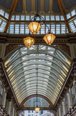 Londra, İngiltere - 27 Haziran 2025 - Tavanın dekoratif Viktorya dönemi mimarisi ve Leadenhall Pazarı içindeki renkli dekorasyonlar. Süslü, işlenmiş demir, cam çatının doğal ışığın pazar alanını aydınlatmasına olanak sağlayan bir kombinasyonu. Metin için boşluk.
