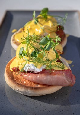 İngiliz çöreği, ızgara domuz pastırması, haşlanmış tavuk yumurtası ve seramik tepside servis edilen hollandez sosu ve su teresiyle yapılmış yumurta. Metin, Seçici odak için Duvar Kağıdı, Poster ve Boşluk olarak kullan.