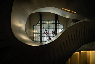 Zarif kıvrımlar ve arka planda Fransa Ulusal Kütüphanesi (BNF) içinde cam tavan olan karmaşık tasarım içeren Grand Helical merdivenlerine bakıyorum. Paris 'te eski ve yeni mimari öğeleri olan etkileyici bir mimari..