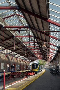 Windsor, İngiltere - 3 Nisan 2025 - Windsor & Eton Riverside tren istasyonu Windsor, Berkshire 'da iki farklı kavisli platformu ve Viktorya dönemi lambaları ile hareket etmeyi bekleyen bir tren, kırmızı tamponlar ve banliyö bisikletleri, duvar kağıdı olarak kullanın..