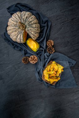 Siyah taş dokusunda ev yapımı çıtır balkabağı cipsi ile düz konum kompozisyonu. Üst görünüm.