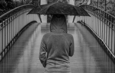 Young asian woman hold Umbrella and crossing on a wooden bridge on a rainy day.