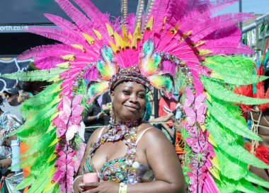 Sanatçı, Notting Hill Karnavalı 'nın büyük, tüylü başlığı ve süslü mücevherleriyle süslü renkli ve çetrefilli bir kostüm giyerek Karayip kültürü ve tarihi kutlamalarıyla tanınıyor.