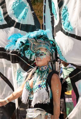 Sanatçı, Notting Hill Karnavalı 'nın büyük, tüylü başlığı ve süslü mücevherleriyle süslü renkli ve çetrefilli bir kostüm giyerek Karayip kültürü ve tarihi kutlamalarıyla tanınıyor.