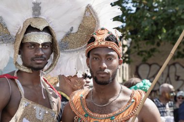 Batı Londra 'daki Notting Hill Karnavalı' nda büyük tüylü bir başlık ve süslü mücevherlerle süslenmiş canlı ve çetrefilli bir kostüm giymiş bir sanatçı. Notting Hill Karnavalı Karayip kültürünü kutlamalarıyla tanınır..