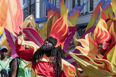 Notting Hill Karnavalı 'nda büyük, alev benzeri başlıklar ve akıcı elementlerle süslü, renkli kostümler giyen bir sanatçı, Karayip kültürünü ve tarihini özenle tanımlayan ve özenle hazırlanmış geçit törenleriyle tanınıyor..