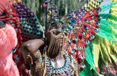 Batı Londra 'daki Notting Hill Karnavalı' nda büyük tüylü bir başlık ve süslü mücevherlerle süslenmiş canlı ve çetrefilli bir kostüm giymiş bir sanatçı. Notting Hill Karnavalı Karayip kültürünü kutlamalarıyla tanınır..