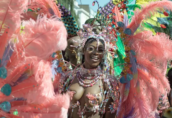 Batı Londra 'daki Notting Hill Karnavalı' nda büyük tüylü bir başlık ve süslü mücevherlerle süslenmiş canlı ve çetrefilli bir kostüm giymiş bir sanatçı. Notting Hill Karnavalı Karayip kültürünü kutlamalarıyla tanınır..