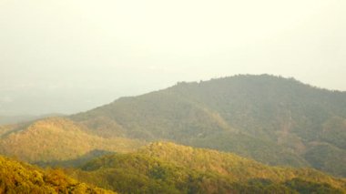 Gün batımında, ulus parkında, dağların tepesindeki yeşil ağaçların görüntüsü. Gökyüzünde turuncu bir su sıçraması. Güzel doğa arka plan konsepti. kamera görüntüsü.