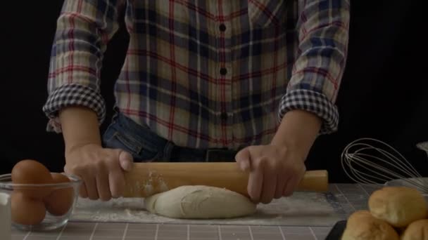 生地を使った職人パン 生地に小麦粉ダスト 手作りパン生地圧延し パン屋の機器ツールとキッチンで混練 黒の背景 仕事中のプロのパン職人 60Fps — ストック動画