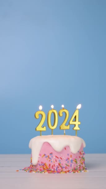 明けましておめでとうございます2024年 新年のお祝いパーティーのための黄金のろうそく番号2024のかわいいケーキのシームレスなループが点灯しました キャンドルウィックの揺れで炎とブルーの背景 — ストック動画