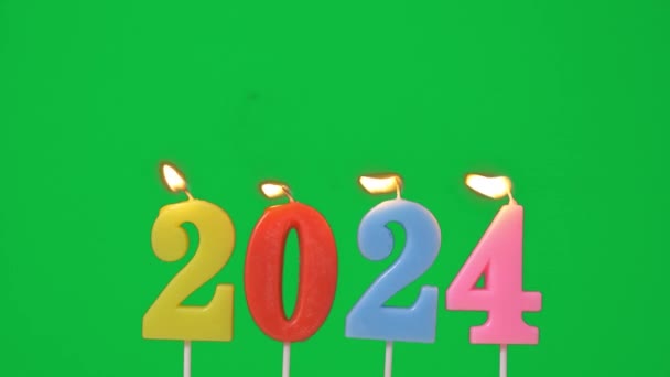 新年快乐2024 彩灯编号2024 新年庆祝晚会点燃 灯芯绒摇杆处的火焰 在绿色屏风背景下被吹灭 水平框架速度60P — 图库视频影像