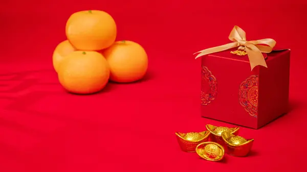 Chinese Lunar New Year red background. ancient Chinese ingot gold bar, orange, red gift box with golden bow decorate for Chinese new year celebrate with wood antique window shadow on the ground