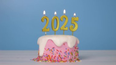 Mutlu yıllar 2025, yeni yıl kutlaması için 2025 numaralı altın mumlu kusursuz pasta döngüsü yakıldı. Candlewick 'teki alevler mavi arka planda titreşiyor, yatay 