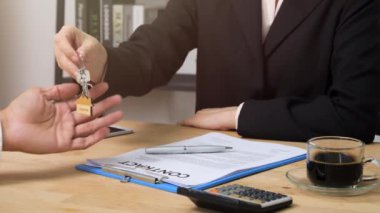 Emlakçının müşteriye ev anahtarı vermesi ve konut sigortası için ipotek kredisi teklifi ve ev sigortası için onaylanmış mortgage başvurusu formuyla sözleşme imzaladıktan sonra el sıkışması.