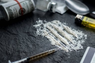 Uyuşturucu bağımlılığı sorunu konsepti. Kokain tozu, eroin, şırınga, kaşık, uyuşturucu aletleri için çakmak ve yasadışı uyuşturucu ticaretinden gelen dolar faturası, sosyal sorunlar