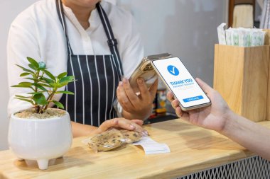 Kafe restoranında cep telefonuyla dijital cüzdan kullanan bir müşteri. Nakitsiz toplum, QR kod taraması ve mobil bankacılık konseptiyle para transferi