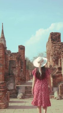 Yalnız gezgin konsepti. Kırmızı elbiseli mutlu bir Asyalı kadın turist. Tayland 'daki Ayutthaya Dünya Mirası sahasında kültür turizmi için tarihi bir tapınağın etrafında dolanıyor.