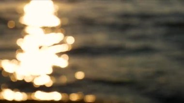 Güneş ışığından yansıyan altın bokeh ışığı gün batımında deniz dalgalanması yüzeyinde