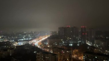 Gece sisli şehir, evlerden, arabalardan ve gece gökyüzündeki bulutlardan gelen ışıklar. Yüksek kalite 4k görüntü