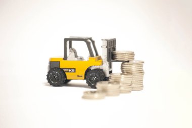 Bir forklift, demir çubuklar şeklinde büyüyen bir grafiğe karşı madeni para kaldırıyor. Bu, iş büyümesini, karı ve finansal başarıyı simgeliyor. Finans, yatırım veya işletme üzerine makaleler ve sunumlar için mükemmel.