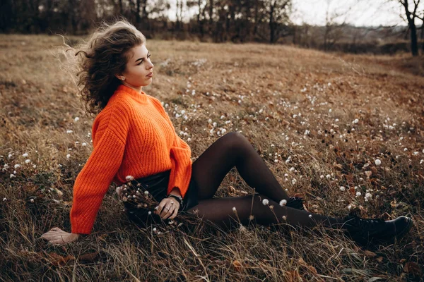 在秋天公园的背景下 美丽的微笑 卷曲的黑发 穿着橙色毛衣的年轻卷曲女孩 背景是秋天的自然 — 图库照片