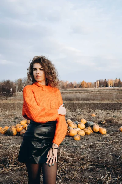 공원의 배경에는 곱슬곱슬 곱슬곱슬 미소를 오렌지 스웨터를 곱슬머리의 가을의 배경에 스톡 사진