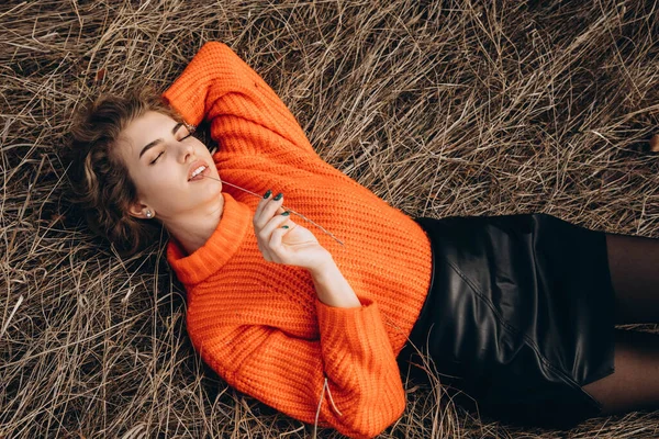 공원의 배경에는 곱슬곱슬 곱슬곱슬 미소를 오렌지 스웨터를 곱슬머리의 가을의 배경에 스톡 이미지
