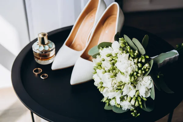 흰색과 백합의 결혼식 꽃다발은 리본으로 장식되어 있으며 옆에는 베이지색 어두운 스톡 사진