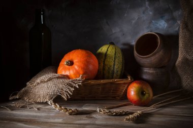 Tahta bir masada üç balkabağı ve eski çanak çömlek.