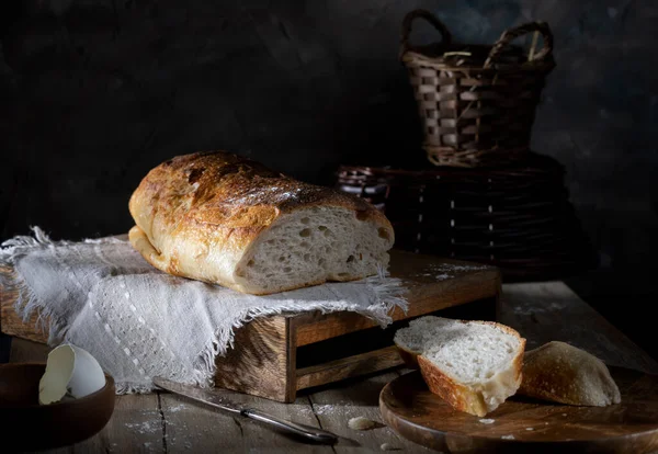 木のテーブルの上で自家製の新鮮な小麦パンをスライス — ストック写真