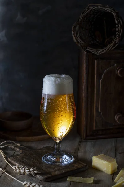 Glass of beer and sliced cheese on rustic table