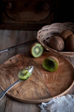 Kahverengi bir tabakta dilimlenmiş kivi meyvesi.