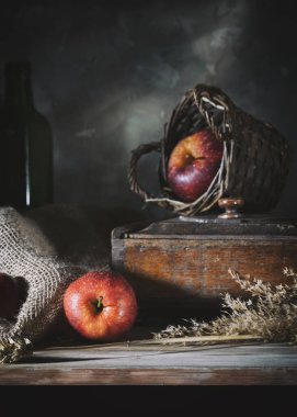 Red apples on a rustic table against a gray wall