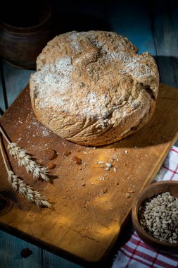 Tahta kesme tahtasının üzerinde yuvarlak ev yapımı ekmek.